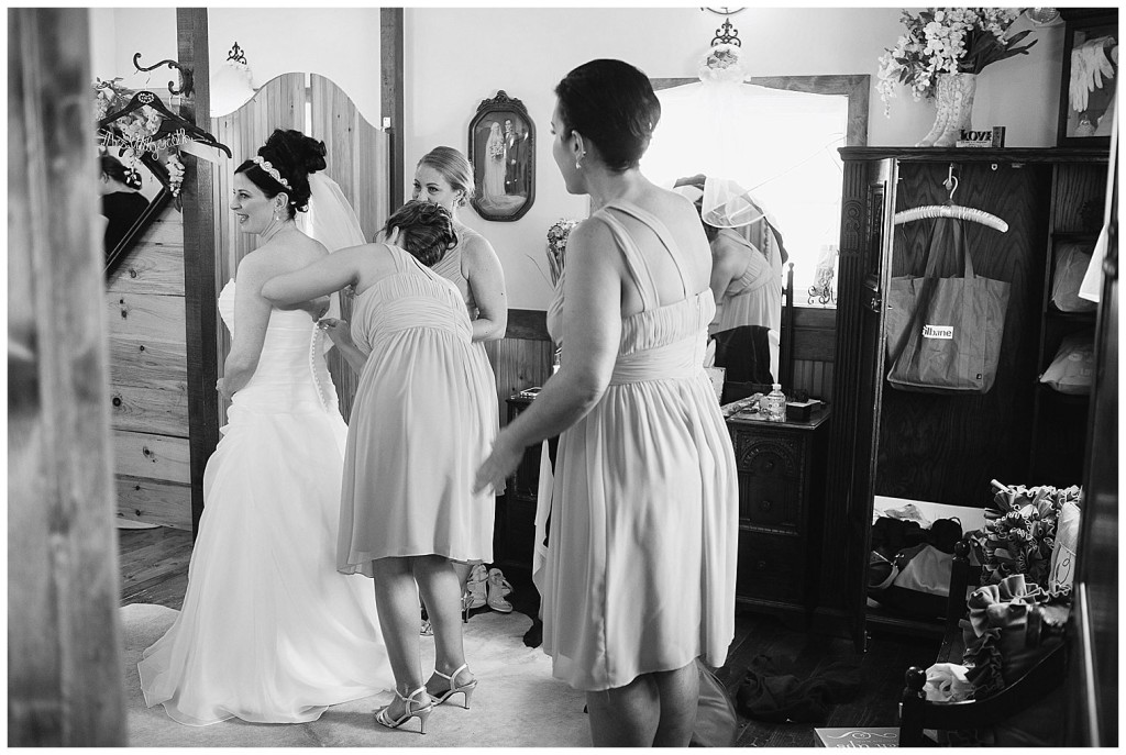 Bridesmaid helping bride getting her wedding dress on.